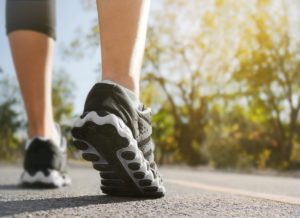 Athlete runner feet running on road closeup on shoe with nature background