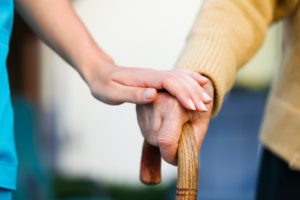 Doctor holding a senior patients 's hand on a walking stick