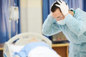 doctor or surgeon upset, holding his head. patient in the background