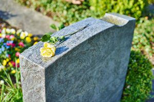 A yellow rose sits atop a gravestone
