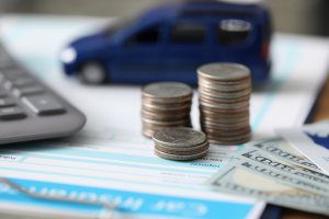 Money and toy cars sit atop a car accident settlement agreement